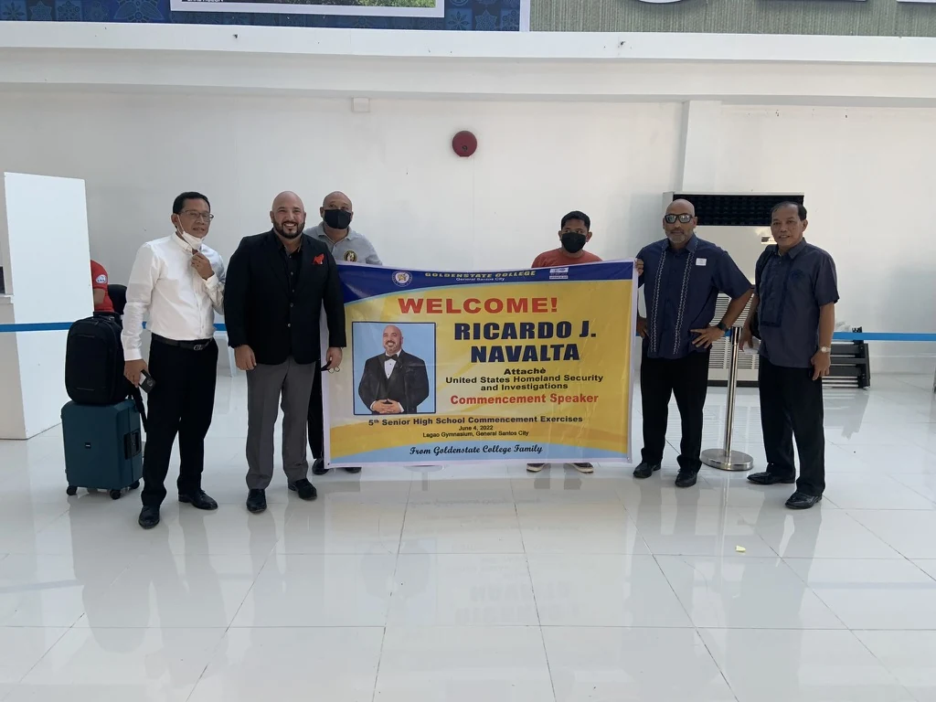 Ricardo beside a welcome banner at Goldenstate College